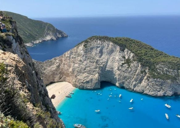 Overlooking a white sandy beach that's framed by cliffs and edged by electric blue water